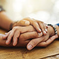 a pair of woman’s hands holding another woman’s hand on a table.